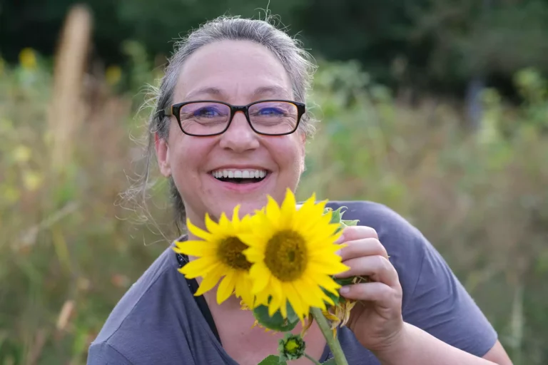 Anja Liedtke strahlt und schenkt zwei gelbe Sonnenblumen