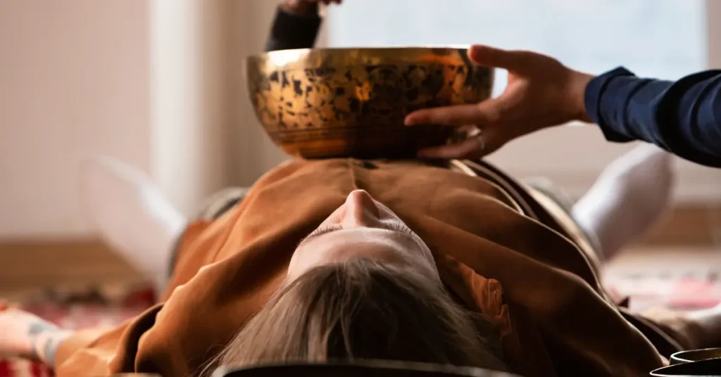 Frau bekommt Klangschalenmassage mit Klangschale auf dem Bauch